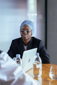 African businesswoman wearing headscarf using laptop during an office meeting.